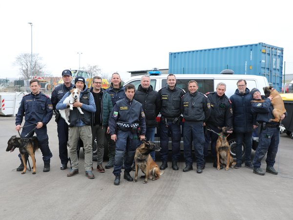 Gruppenfoto von Polizisten mit ihren Diensthunden sowie Vertretern der Stadt am Wirtschaftshof vor einem Polizeiauto