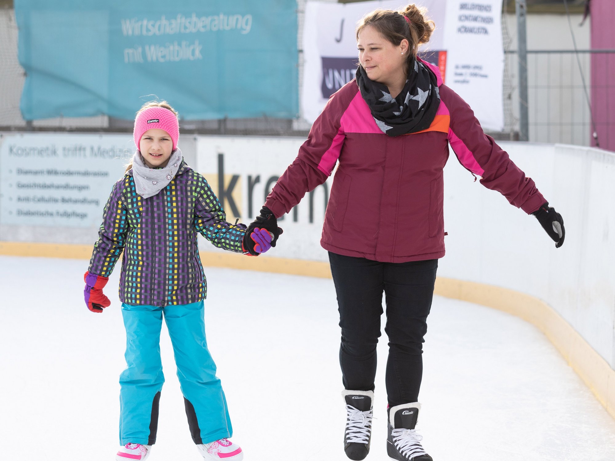 Frau und Mädchen Hand in Hand beim Eislaufen auf der Kremser Kunsteisbahn