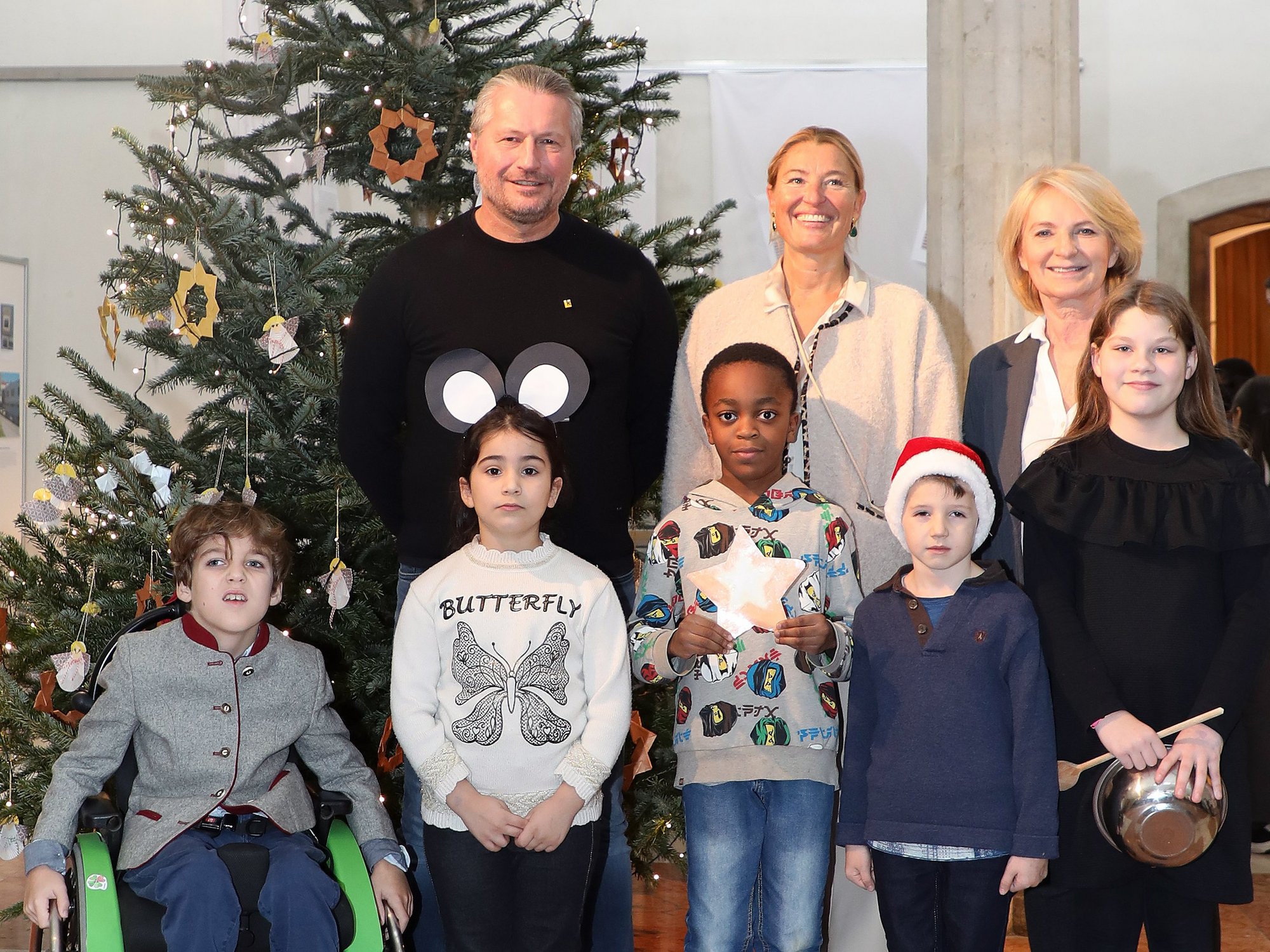 Bürgermeister, Vizebürgermeisterin und Schulleiterin zusammen mit fünf Kindern vor dem Weihnachtsbaum im Rathaus