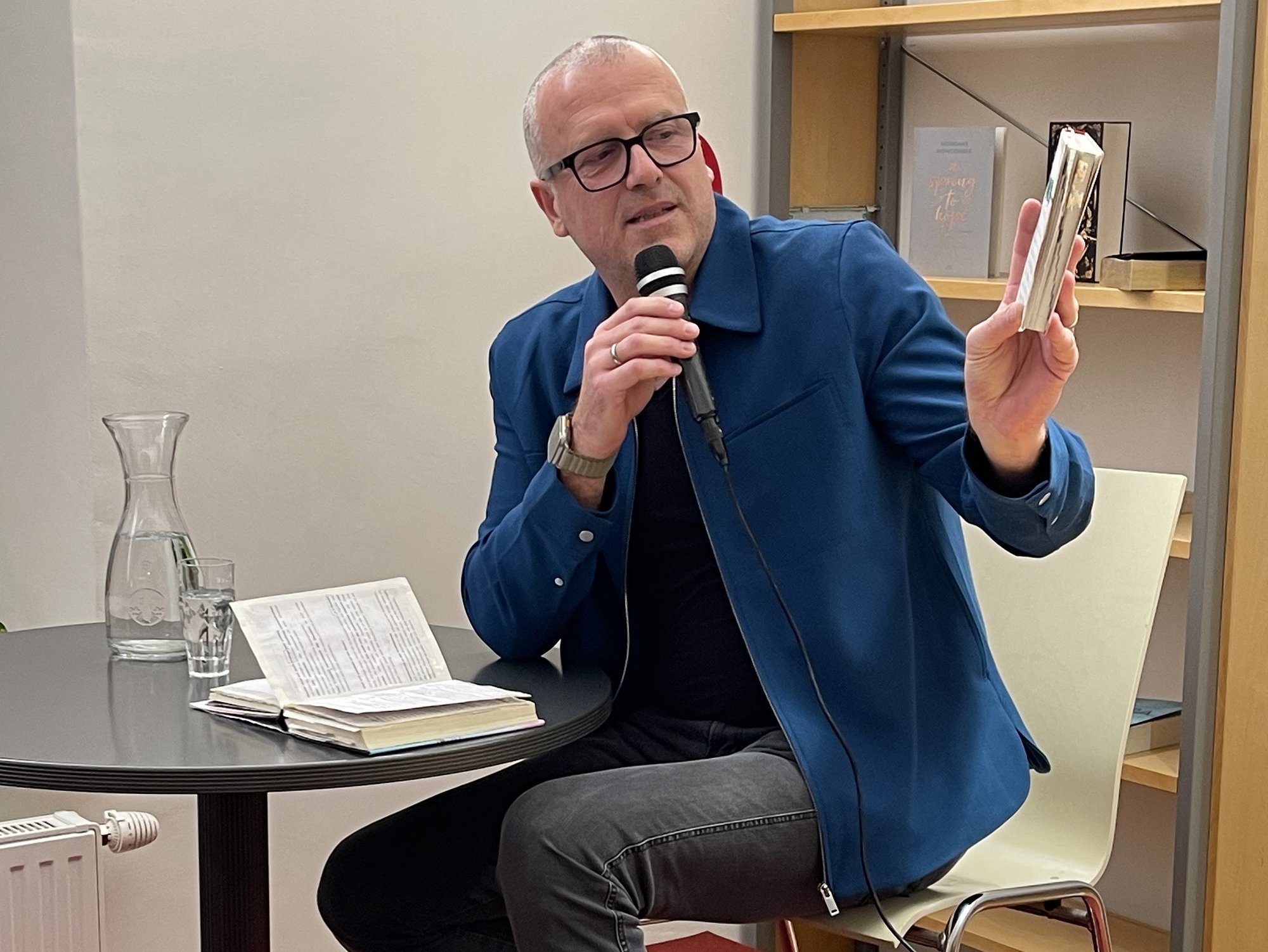 Autor Bernhard Aichner mit Mikrofon und einem Buch in der Hand