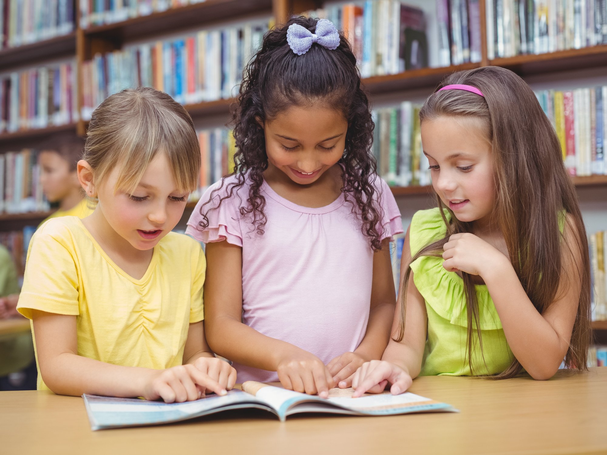 Pupils reading book together in library