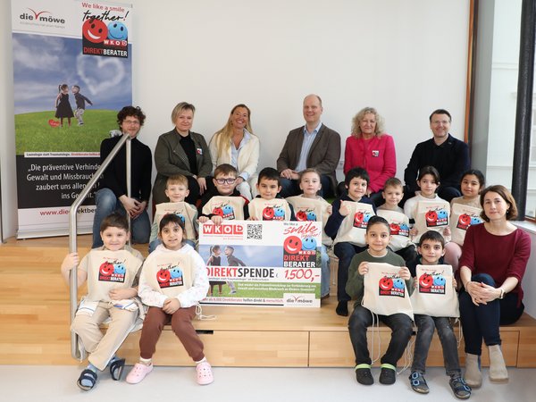 Eine Gruppe von Kindern und Erwachsenen posiert mit Spendenplakat und Stofftaschen der Initiative „Direktberater NÖ“ für ein Gruppenfoto.