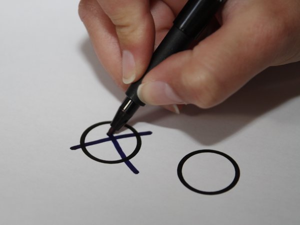 Bild einer Hand, die mit einem Stift ein Wahlkreuz macht