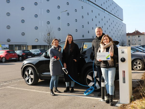 Umwelt- und Mobilitätsstadträtin Alexandra Ambrosch, Bewohnerin Sarah Tiefenbacher, Bürgermeister Peter Molnar und Stefanie Widhalm (Managerin der Klima- und Energiemodellregion Krems) mit einem Auto an der Landestation in der Reitenhaslachergasse, im Hintergrund ein großer Wohnbau